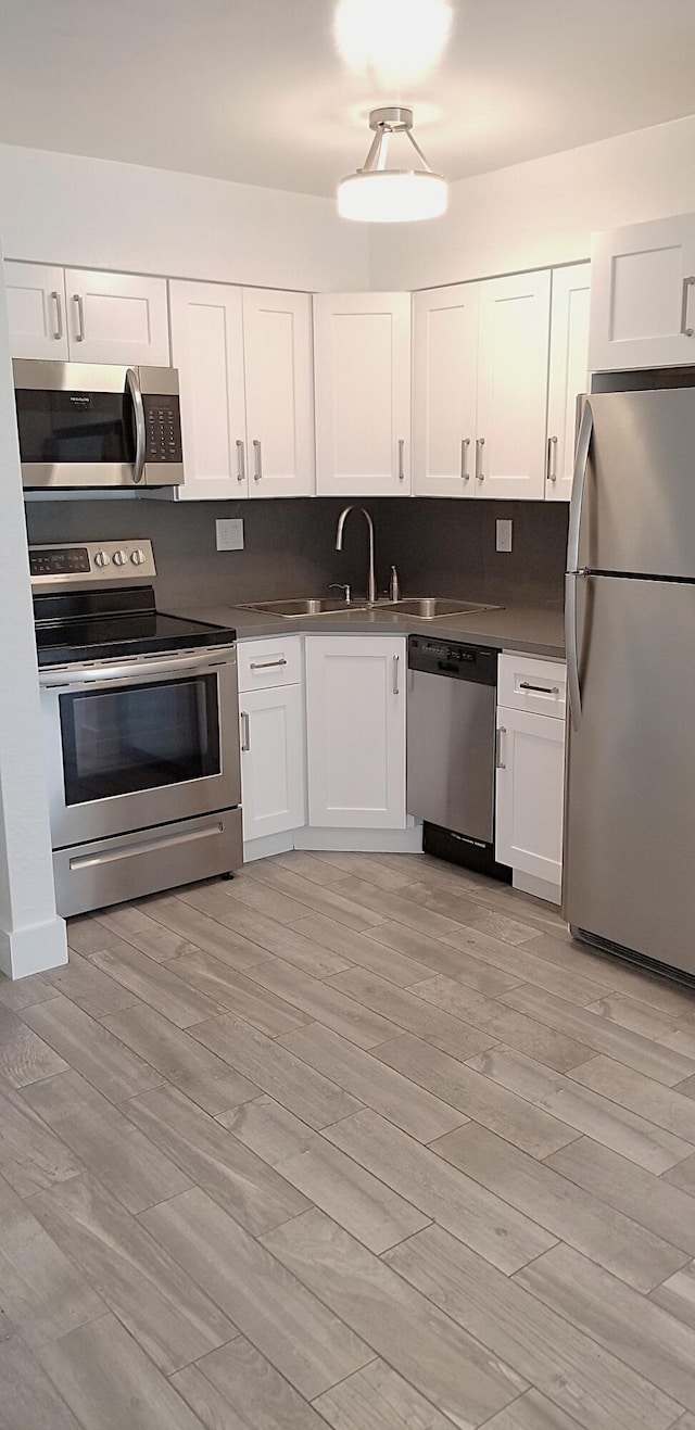 kitchen featuring stainless steel appliances, white cabinets, and light wood-type flooring