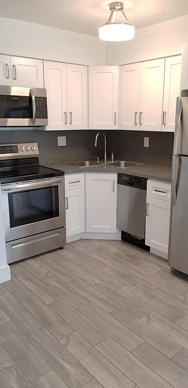 kitchen with light hardwood / wood-style flooring, white cabinets, sink, and stainless steel appliances