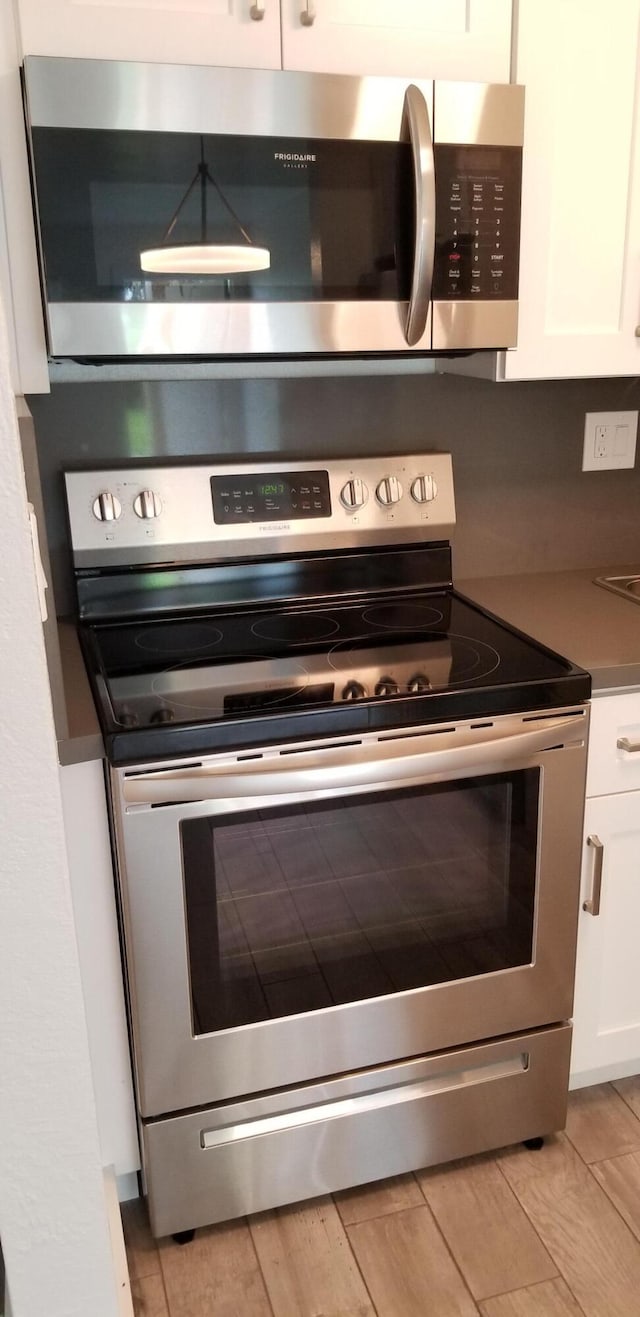 details featuring white cabinetry, light hardwood / wood-style flooring, and appliances with stainless steel finishes