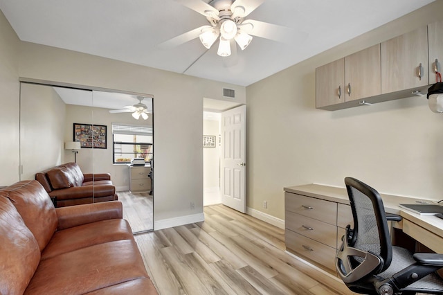 home office with light hardwood / wood-style floors and ceiling fan