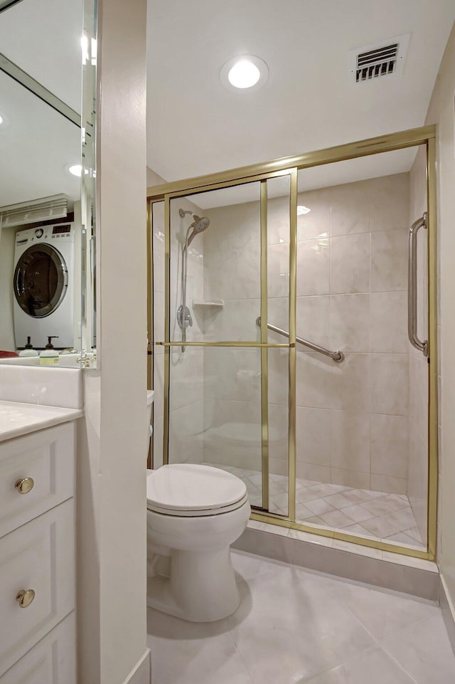 bathroom with walk in shower, vanity, stacked washer and clothes dryer, tile patterned flooring, and toilet