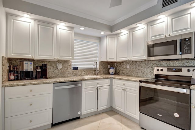 kitchen with ornamental molding, stainless steel appliances, sink, white cabinetry, and light tile patterned flooring