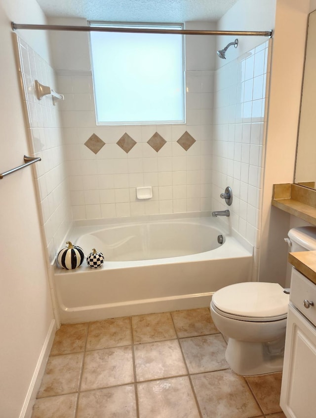 full bathroom featuring toilet, tile patterned flooring, tiled shower / bath, a textured ceiling, and vanity