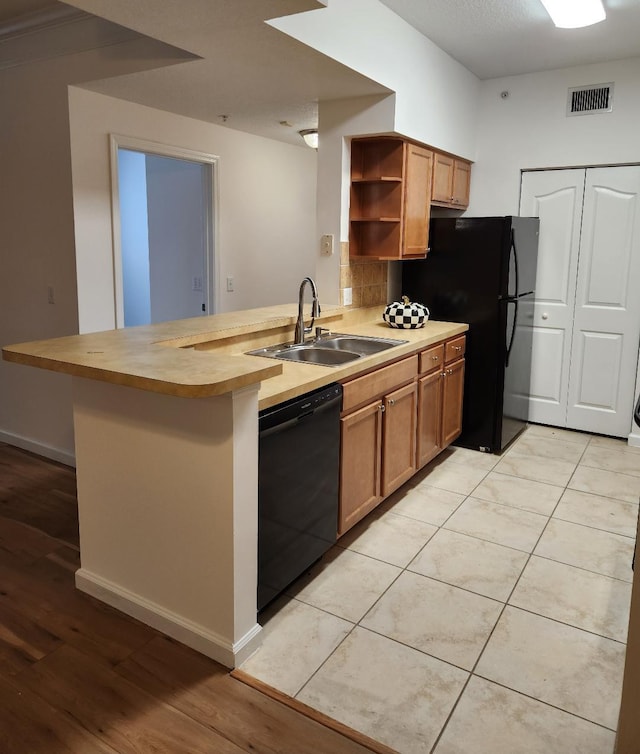 kitchen featuring kitchen peninsula, decorative backsplash, black appliances, sink, and light tile patterned floors