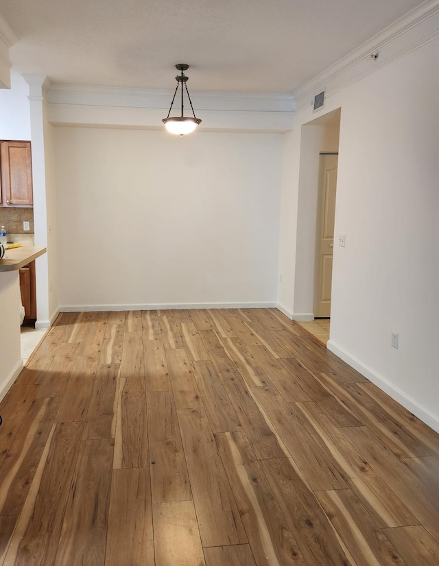 unfurnished dining area with ornamental molding and light hardwood / wood-style floors