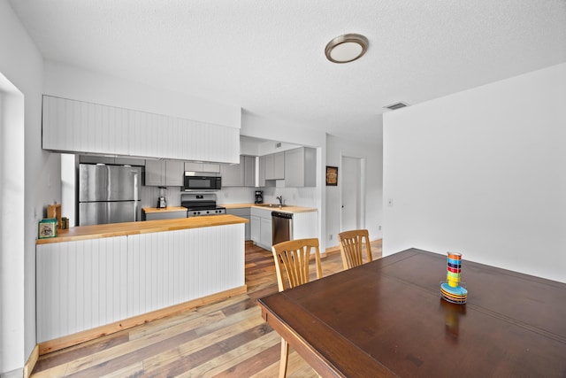 dining area with visible vents, a textured ceiling, and light wood finished floors