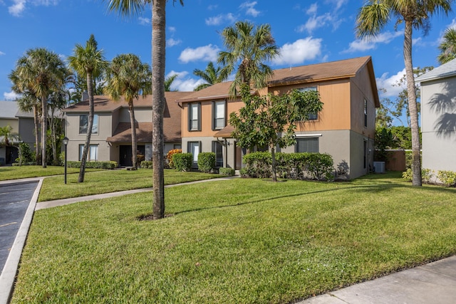 townhome / multi-family property featuring central AC, a front lawn, and stucco siding