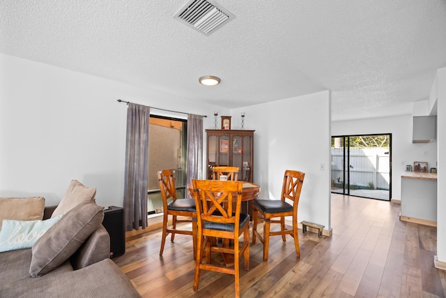 dining area featuring visible vents, a textured ceiling, and wood finished floors