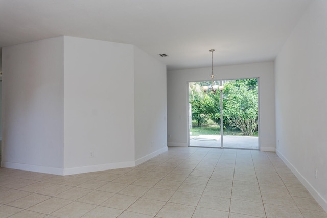 unfurnished room with a chandelier and light tile patterned floors