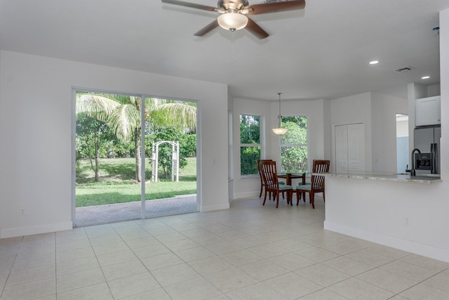 tiled living room with plenty of natural light and ceiling fan