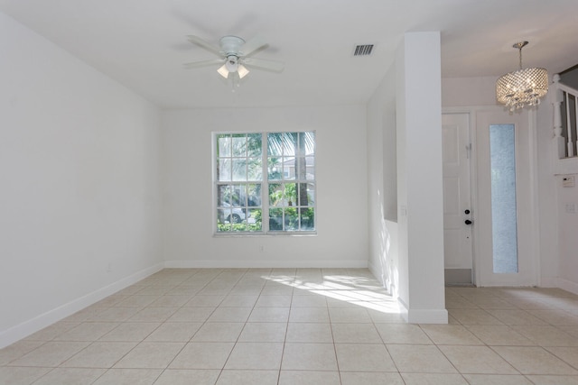 tiled spare room with ceiling fan with notable chandelier