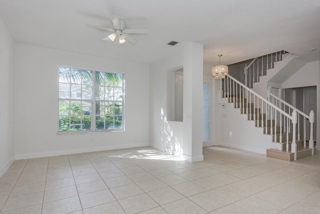 tiled empty room featuring ceiling fan with notable chandelier