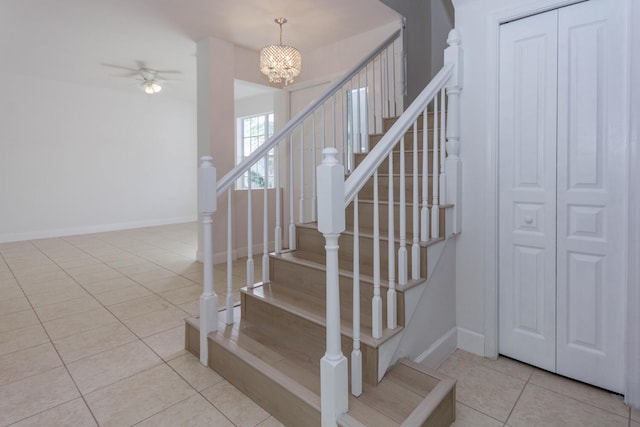 stairs with tile patterned flooring and ceiling fan with notable chandelier