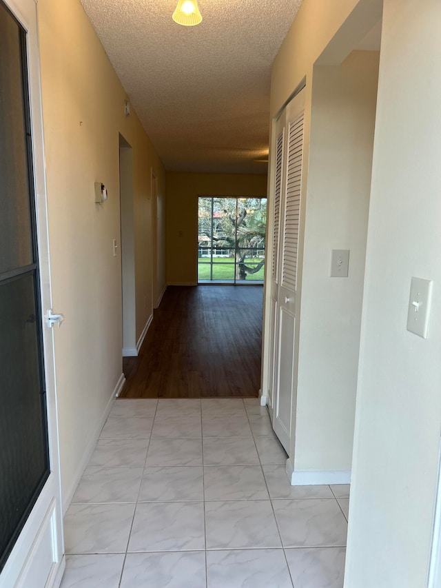 corridor featuring a textured ceiling and light hardwood / wood-style flooring