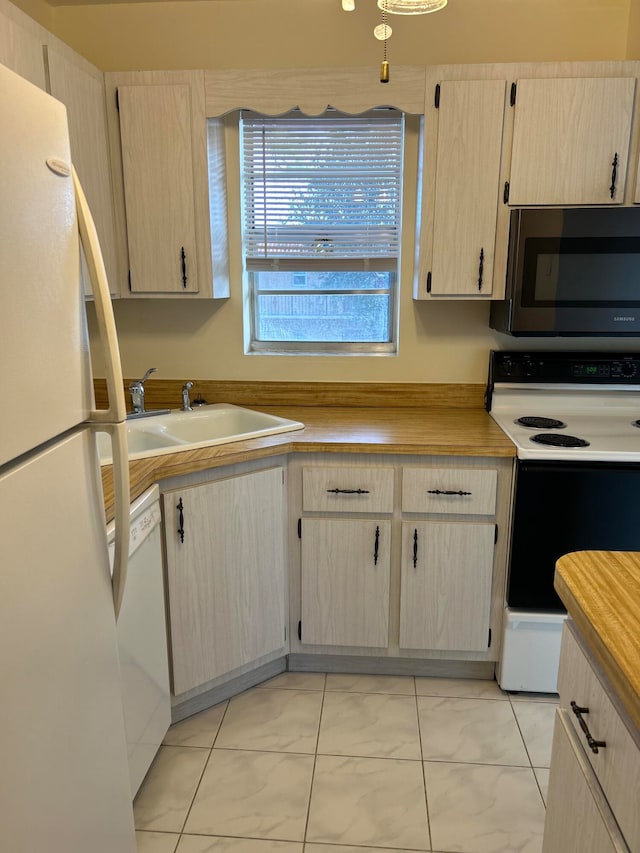 kitchen with white appliances, light brown cabinetry, and sink