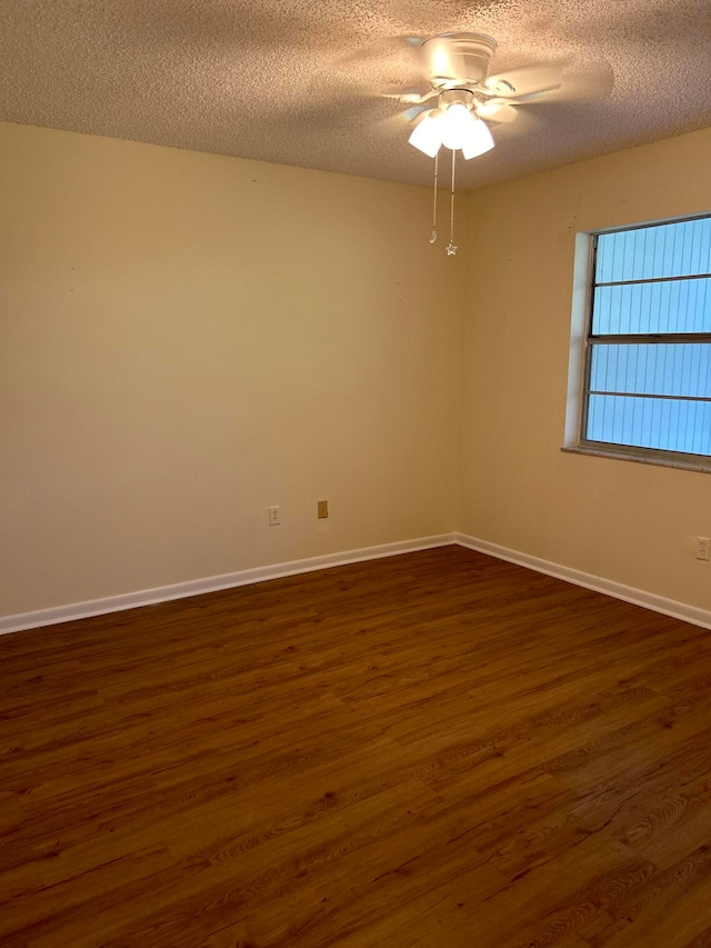 empty room with dark hardwood / wood-style floors, a textured ceiling, and ceiling fan