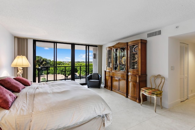 bedroom featuring access to exterior, a textured ceiling, a closet, and floor to ceiling windows