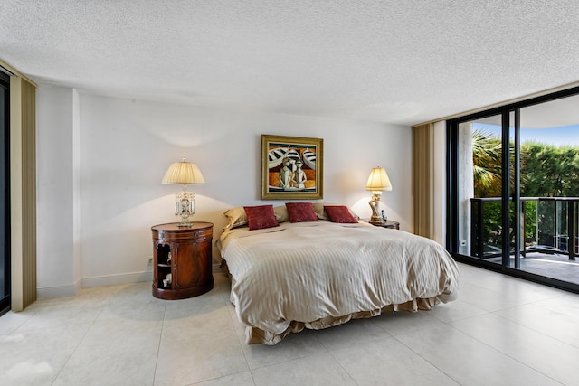 bedroom with access to exterior, a textured ceiling, and a wall of windows