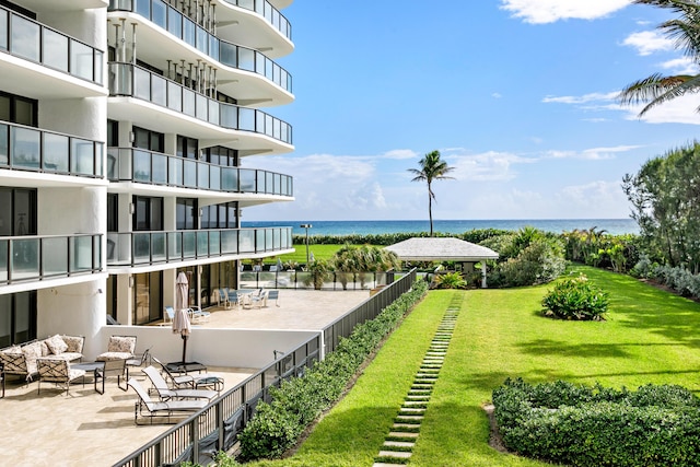 surrounding community with a water view, a patio area, and a lawn