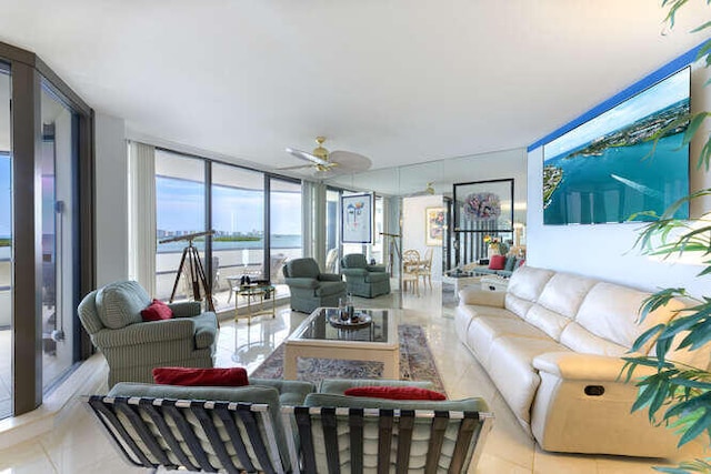 tiled living room with a water view, ceiling fan, and expansive windows