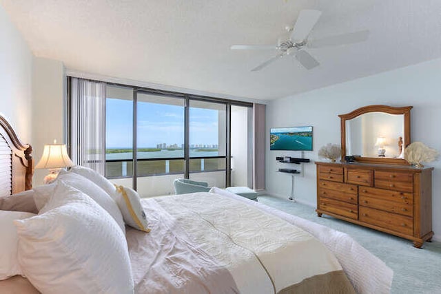 carpeted bedroom featuring expansive windows, access to outside, and ceiling fan