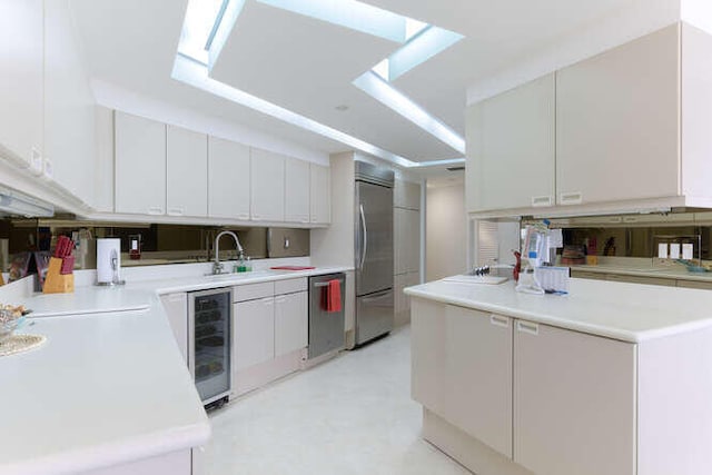 kitchen with white cabinetry, sink, wine cooler, and stainless steel appliances