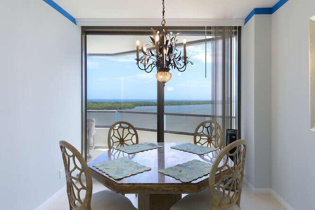 dining room featuring crown molding, a chandelier, and a water view