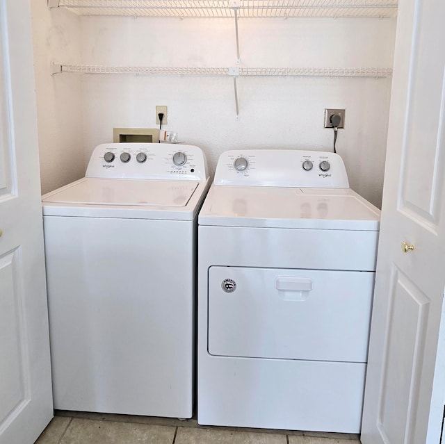 clothes washing area with light tile patterned floors and washer and clothes dryer