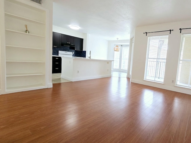 unfurnished living room featuring built in shelves and light hardwood / wood-style flooring