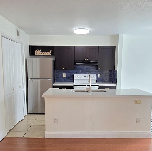 kitchen featuring dark brown cabinets, sink, electric stove, stainless steel refrigerator, and light tile patterned flooring