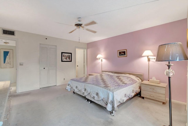 bedroom with ceiling fan, light carpet, and a closet