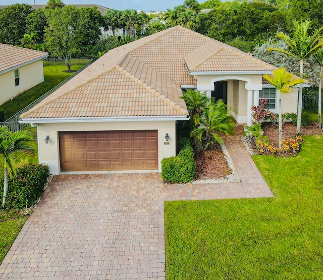 mediterranean / spanish-style home with a garage and a front lawn