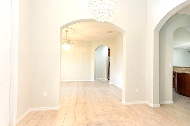 unfurnished room featuring light hardwood / wood-style flooring and a notable chandelier