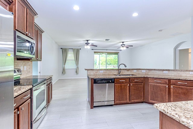 kitchen featuring backsplash, appliances with stainless steel finishes, light stone countertops, light hardwood / wood-style flooring, and sink