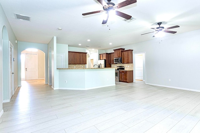 kitchen with appliances with stainless steel finishes, tasteful backsplash, and light hardwood / wood-style floors