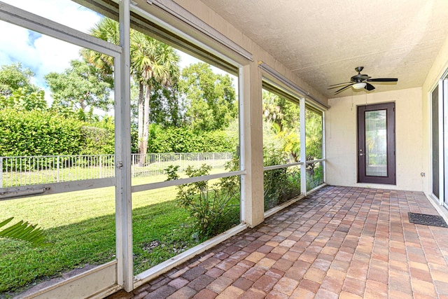 unfurnished sunroom featuring ceiling fan