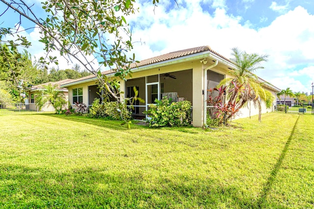 rear view of house with ceiling fan and a lawn