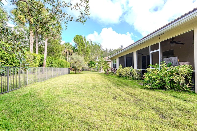 view of yard featuring a sunroom and ceiling fan