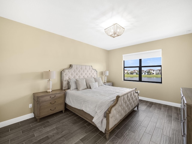 bedroom with dark wood-type flooring and a water view