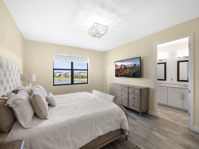 bedroom featuring ensuite bathroom, sink, and light hardwood / wood-style floors