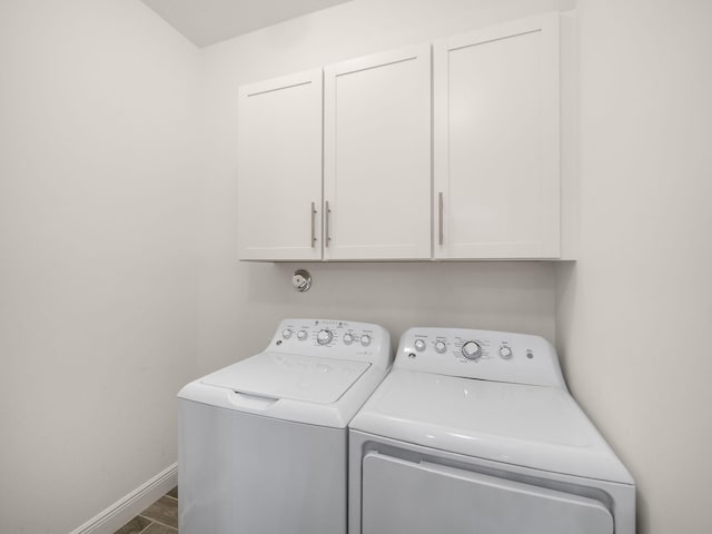 clothes washing area featuring washing machine and dryer and cabinets