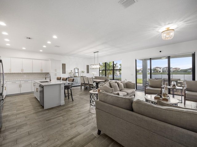 living room featuring a notable chandelier, sink, wood-type flooring, and a water view