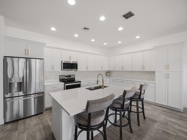 kitchen with white cabinetry, appliances with stainless steel finishes, sink, and wood-type flooring