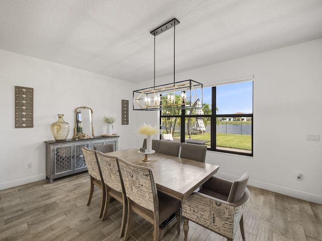 dining area featuring hardwood / wood-style flooring, a textured ceiling, and an inviting chandelier