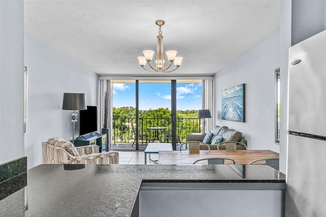 living room featuring a textured ceiling, an inviting chandelier, and expansive windows