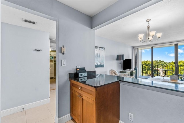 kitchen featuring a notable chandelier, light tile patterned flooring, hanging light fixtures, and dark stone counters