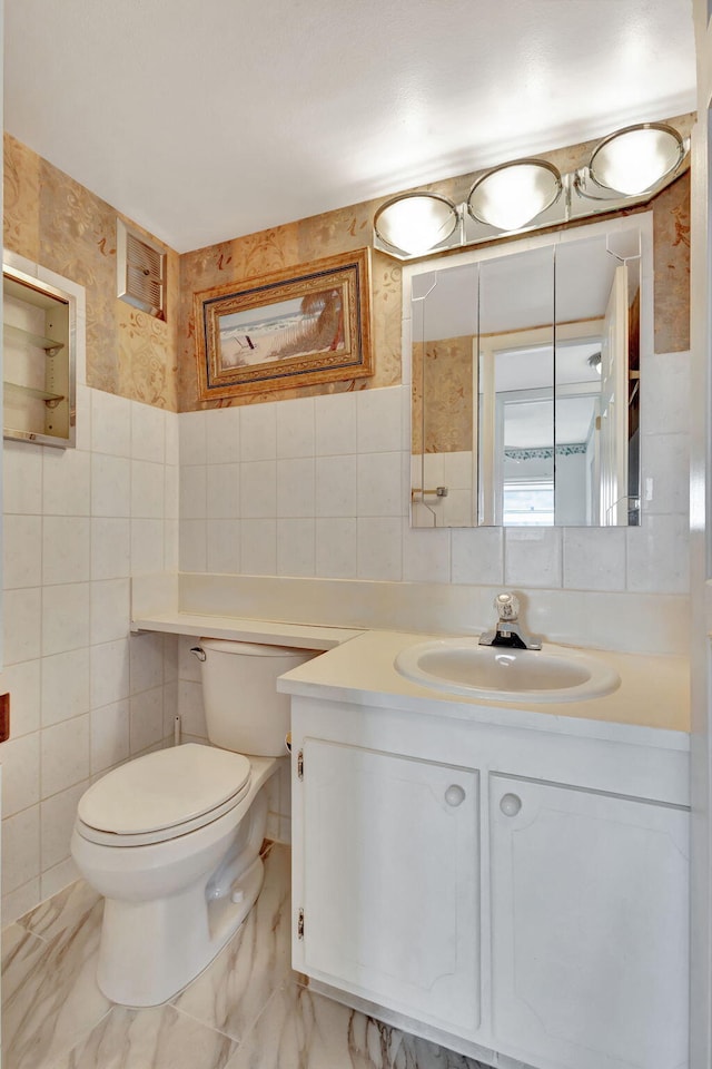 bathroom featuring vanity, toilet, and tile walls