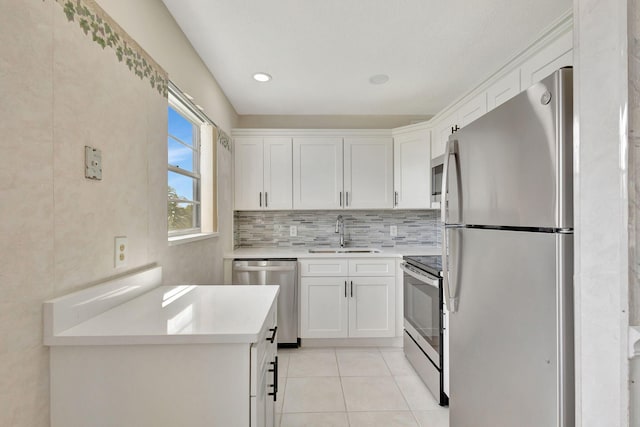 kitchen with stainless steel appliances, sink, light tile patterned flooring, white cabinets, and tasteful backsplash