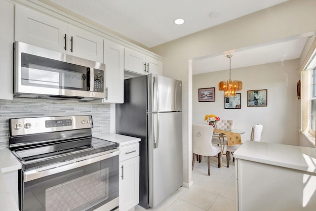 kitchen featuring decorative backsplash, hanging light fixtures, an inviting chandelier, white cabinetry, and stainless steel appliances