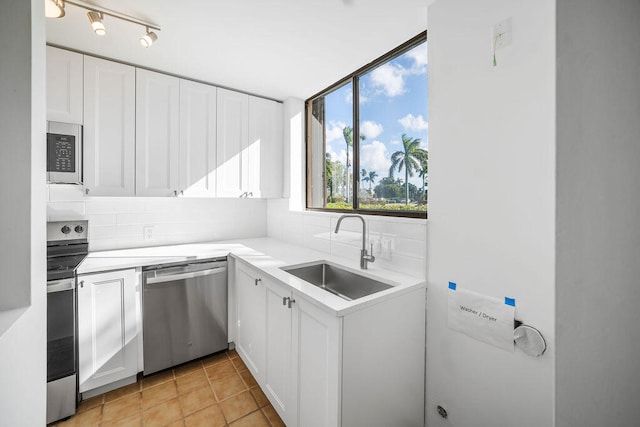 kitchen with sink, light tile patterned floors, tasteful backsplash, white cabinetry, and stainless steel appliances